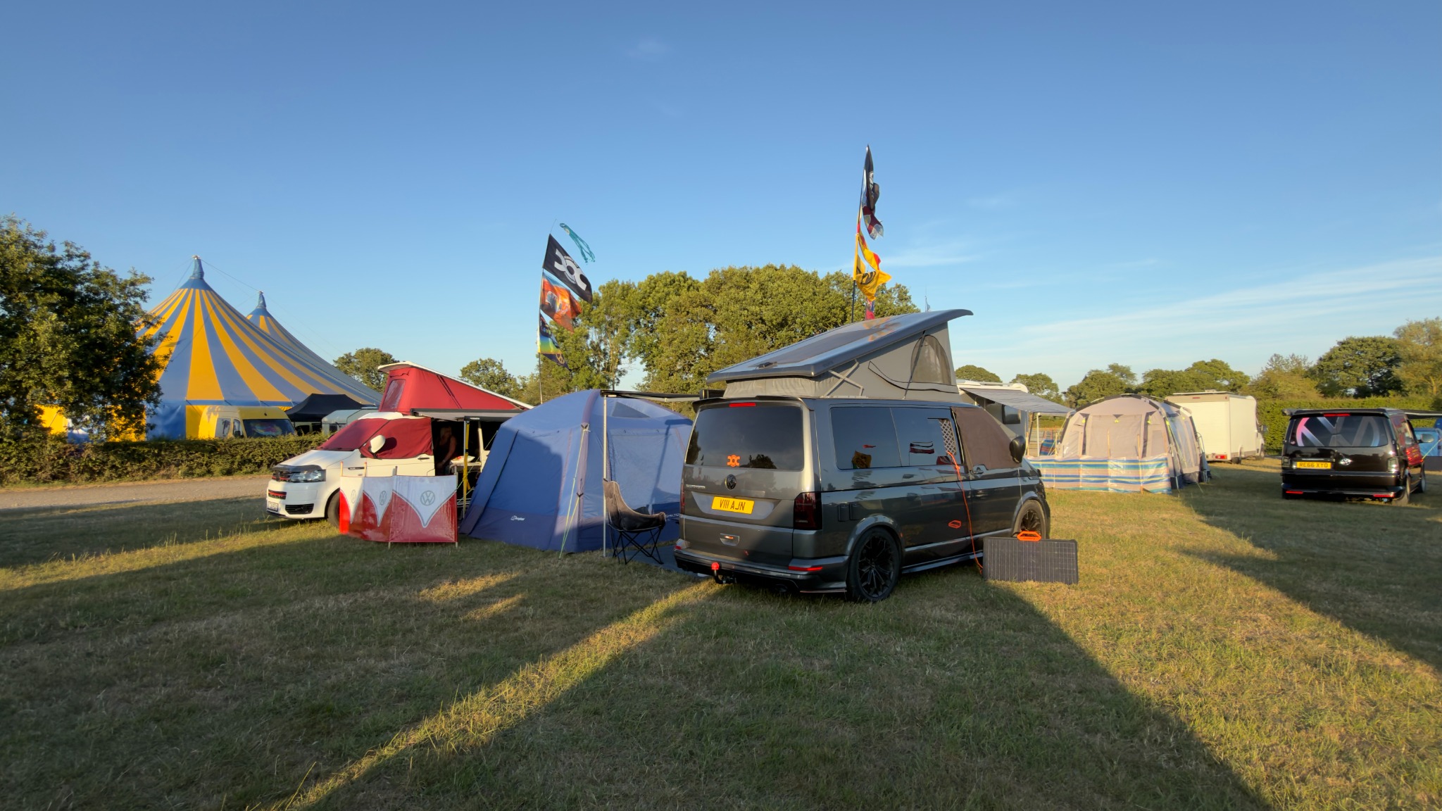 A wide rear view of Vanilla and the campsite at Dubbed Out in warm evening sunshine